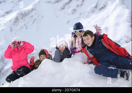 groupe de cinq jeunes garçons et filles au ski costume couché sur la neige blanche dans la station de loisirs de montagne alpine activité Banque D'Images