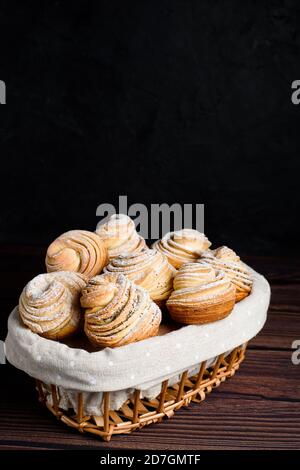 Viennoiseries-cruffins à la mode moderne, muffin feuilletée, un mélange de croissants et de muffins. Sur une table en bois sombre parsemée de sucre en poudre. Placez t Banque D'Images