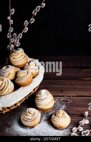 Viennoiseries-cruffins à la mode moderne, muffin feuilletée, un mélange de croissants et de muffins. Sur une table en bois sombre parsemée de sucre en poudre. Placez t Banque D'Images