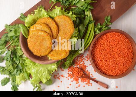 burgers de lentilles et de carottes vegan dans une assiette en bois avec salade verte sur fond clair. aliments sains végétariens. lentilles dans une assiette en bois. Banque D'Images