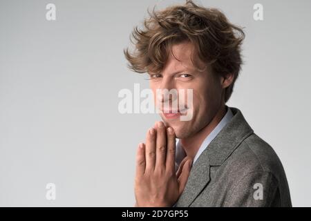 Concept de demande de type. Homme aux cheveux bouclés mignon souriant avec des paumes pliées dans la prière. Gros plan sur un portrait masculin. Copier l'espace sur le côté gauche Banque D'Images