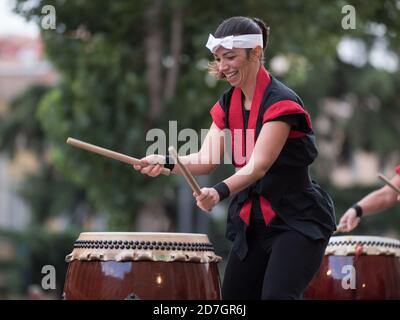 Fille jouant des tambours de la tradition musicale japonaise lors d'un événement public en plein air. Banque D'Images