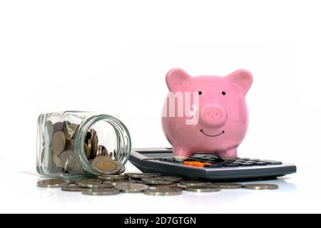 Argent déversant d'un pot d'argent comme une banque de porc sur une calculatrice sur un fond blanc concept de dépenser et d'économiser de l'argent. Banque D'Images
