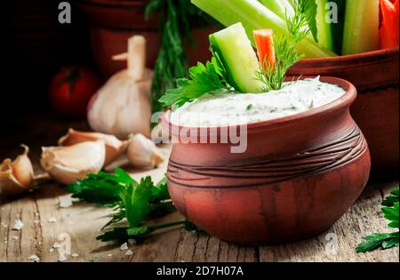Bâtonnets frais carottes, céleri, concombre et sauce blanche avec herbes et épices dans un bol en argile dans un style rustique, foyer sélectif Banque D'Images