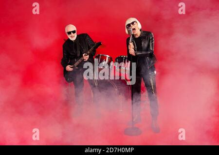 Photo pleine grandeur du groupe de rock funky à deux personnes retraité blanc cheveux gris pensionné femme chanteur chantant homme solo jouer guitare basse ont tour de ventilateur Banque D'Images