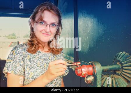 Mécanisme de rotation dans les mains des femmes. La femme dans la cabine d'une locomotive à vapeur. Mécanismes vintage à l'intérieur de l'ancien train. Mode de vie portrait féminin Banque D'Images