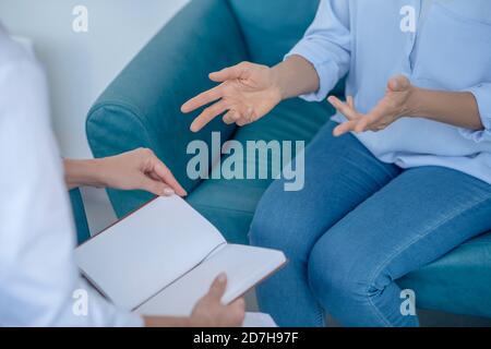 Gros plan des mains de la patiente gesticalant, femme médecin assise face à l'ordinateur portable Banque D'Images