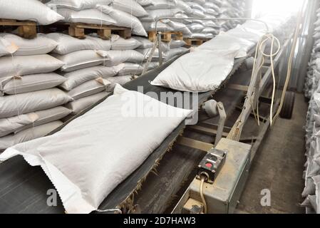 des sacs blancs complets reposent sur le tapis du convoyeur Banque D'Images