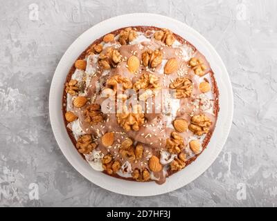 Gâteau fait maison avec crème de lait, cacao, amande, noisette sur fond de béton gris avec textile orange. Vue de dessus, plan d'installation, gros plan. Banque D'Images