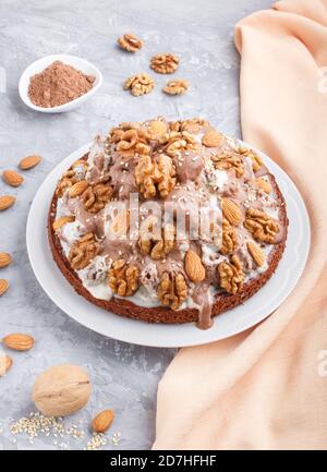 Gâteau fait maison avec crème de lait, cacao, amande, noisette sur fond de béton gris avec textile orange. Vue latérale, gros plan. Banque D'Images