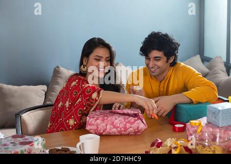 Un jeune couple parle et se regarde les uns les autres tout en emballant Un cadeau pour la fête de Diwali Banque D'Images