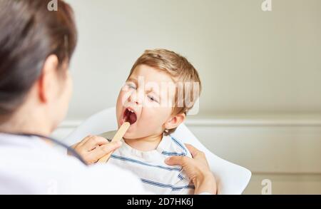 Le pédiatre examine l'enfant avec l'amygdalite ou le mal de gorge avec la spatule Banque D'Images