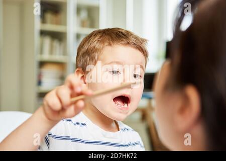 L'enfant examine la gorge du pédiatre avec une spatule pour confiance Banque D'Images