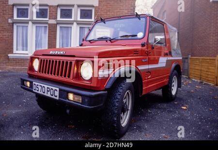 Une jeep Suzuki SJ410 rouge 1987 avec des bandes grises et une capote souple en vinyle gris garée sur la piste d'un bloc d'appartements dans la région de Boscombe à Bournemouth. 06 octobre 1990. Photo: Neil Turner Banque D'Images