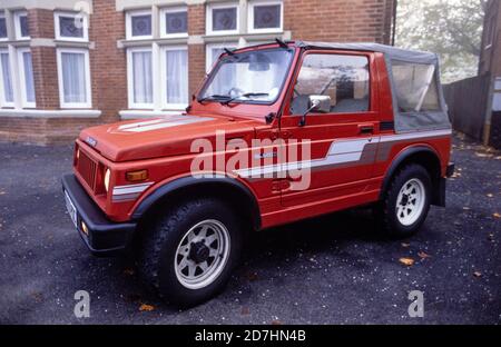 Une jeep Suzuki SJ410 rouge 1987 avec des bandes grises et une capote souple en vinyle gris garée sur la piste d'un bloc d'appartements dans la région de Boscombe à Bournemouth. 06 octobre 1990. Photo: Neil Turner Banque D'Images