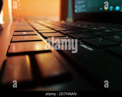 Prise de vue à faible angle du clavier noir d'ordinateur portable pendant le lever du soleil dans la journée ensoleillée Banque D'Images