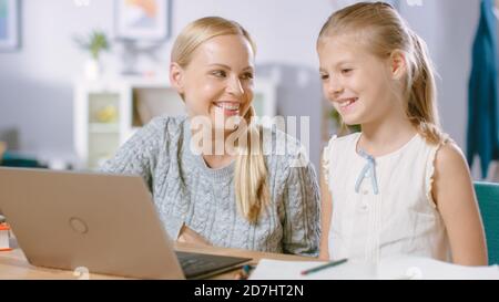 Bright Little Girl Studies avec sa belle école d'étude de la jeune mère leçons à la maison. Une maman dévouée aide sa fille intelligente à faire du travail à domicile. Ils utilisent Banque D'Images