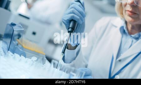 Gros plan de la main dans le gant à l'aide d'une micropipette lors de l'utilisation de tubes à essai. Personnes dans le laboratoire pharmaceutique innovant avec médical moderne Banque D'Images