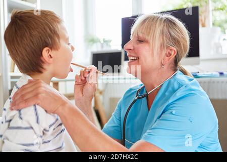 Le pédiatre examine l'enfant avec l'amygdalite ou le mal de gorge avec la spatule Banque D'Images