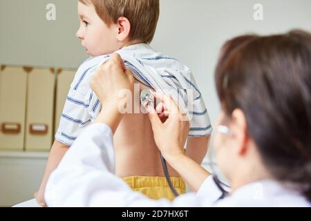 Pédiatre écoutant les poumons d'un enfant sur le dos avec un stéthoscope Banque D'Images