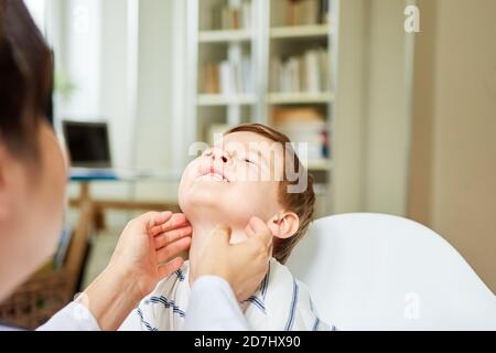 Le pédiatre palate les amygdales et les ganglions lymphatiques chez un enfant avec amygdalite Banque D'Images