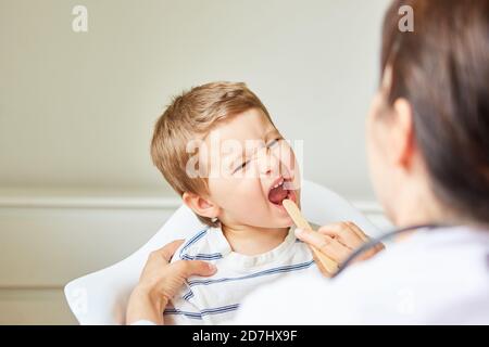 Le pédiatre examine l'enfant atteint d'un mal de gorge ou d'une amygdalite avec une spatule Banque D'Images
