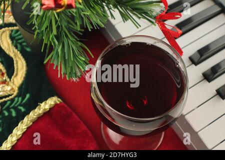 Gros plan d'un verre de vin chaud à côté des clés du piano Avec décorations de Noël Banque D'Images