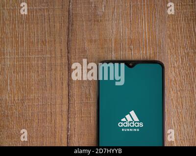 LOD, Israël - 8 juillet 2020 : écran de lancement de l'application Adidas Running avec logo sur l'écran d'un smartphone mobile noir sur fond de bois. Vue de dessus à plat Banque D'Images