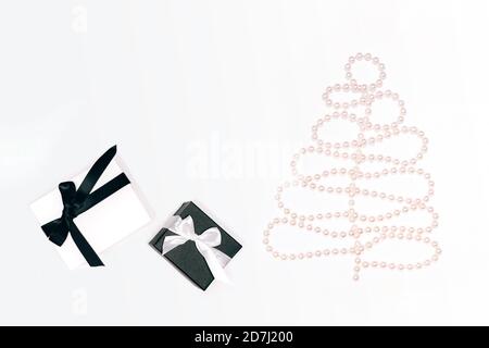 Coffret cadeau ou cadeau blanc avec ruban noir et perles en forme d'arbre de Noël sur fond blanc. Composition de pose pour anniversaire, Noël, mariage. Espace de copie libre pour le texte. Banque D'Images