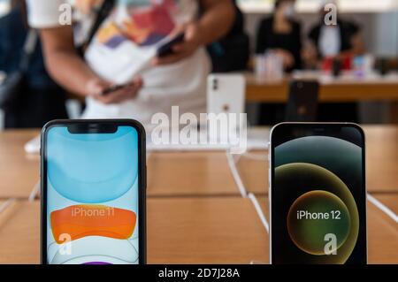 Le nouveau smartphone iphone 12 à côté de l'iPhone 11 en tant que client teste en arrière-plan les produits de marque Apple dans un magasin Apple Store pendant le jour de lancement des nouveaux téléphones iPhone 12 et iPhone 12 Pro. Banque D'Images