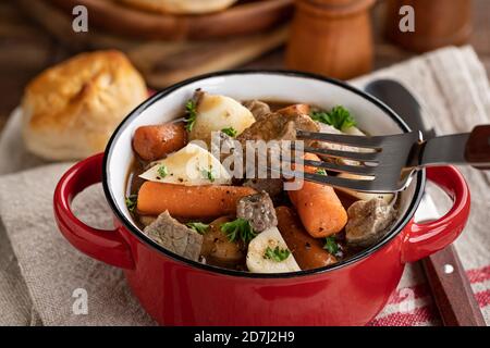Ragoût de bœuf avec carottes et pommes de terre dans un bol rouge et morceau de boeuf sur une fourchette Banque D'Images