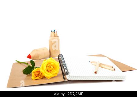 Crayons de couleur, carnets et fleurs roses isolés sur fond blanc. Banque D'Images
