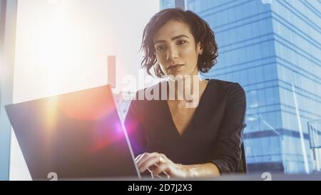 Portrait à angle bas de belle femme exécutive réussie travaillant sur un ordinateur portable dans son bureau moderne Sunny. Chef d'entreprise féminin fort. Banque D'Images