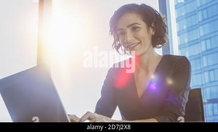 Portrait à angle bas de belle femme exécutive réussie travaillant sur un ordinateur portable dans son bureau moderne Sunny. Chef d'entreprise féminin fort. Banque D'Images