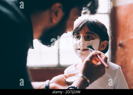 Père peignant le visage de sa fille pour Halloween Banque D'Images