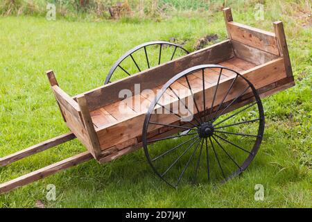 Vide chariot en bois vintage avec roues en métal noir herbe verte le jour de l'été Banque D'Images