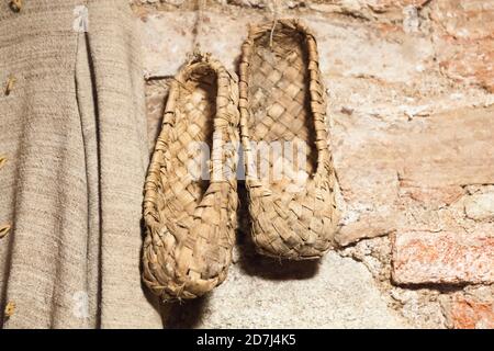 Des chaussures de sport russes vintage sont accrochées au mur de briques. Ces chaussures sont fabriquées à partir de bast ou de fibres provenant de l'écorce d'arbres tels que le linden ou le bouleau Banque D'Images