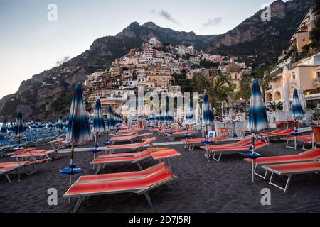 Positano, Italie - 24 2020 août : plage Positano Spiaggia avec chaises de plage et parasols Orange le soir avec vue sur le village Banque D'Images