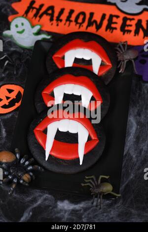Fangs de vampire dépassant des lèvres de scarlet, biscuits glacés de pain d'épice au miel. Idée de nourriture pour Halloween Banque D'Images