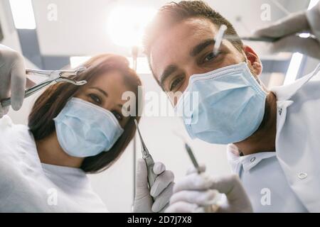 Dentiste et assistante féminine avec instruments médicaux pendant le traitement en clinique Banque D'Images