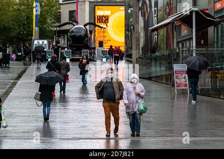 Un homme et une femme marchent le long de New Street à Birmingham en portant des masques, comme la ville est dans Covid Alert Tier 2, High Alert, pendant le temps pluvieux Banque D'Images