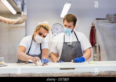 Homme et femme à polir la porte en se tenant près de l'établi à atelier Banque D'Images