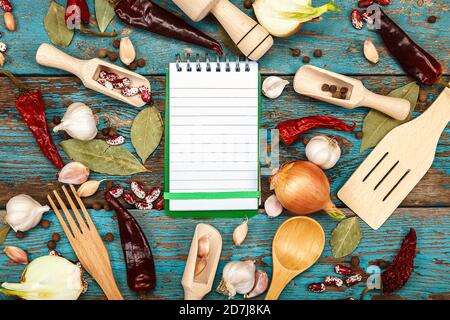 Légumes, épices et carnet de recettes sur fond de bois. Oignon, ail, poivre, feuille de Laurier, haricots. Un ensemble d'ustensiles de cuisine. Accessoires pour c Banque D'Images