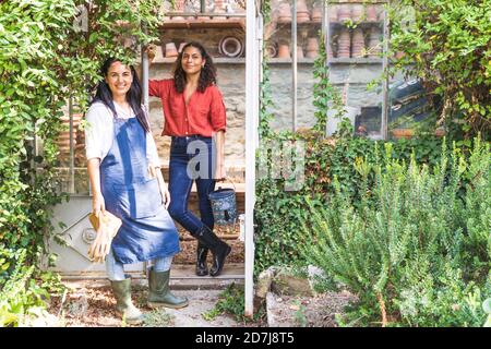 Amis debout dans la cour arrière avec l'équipement de jardinage sur ensoleillé jour Banque D'Images