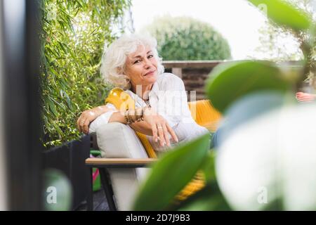 Femme d'âge mûr assise sur un canapé dans le balcon Banque D'Images