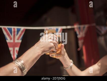 Des amies toastent des verres à bière tout en appréciant le week-end au pub Banque D'Images