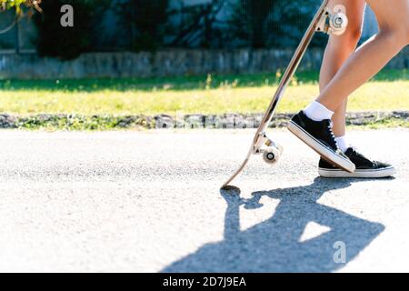 Femme tenant une planche à roulettes tout en marchant sur la route en ville pendant jour ensoleillé Banque D'Images