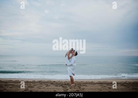 Petit ami romantique transportant une petite amie sur la plage Banque D'Images