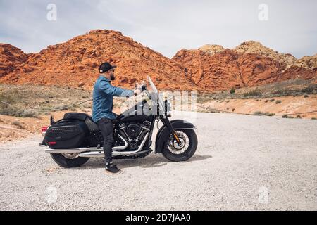 Homme assis à moto au parc régional de la Vallée de feu, Nevada, États-Unis Banque D'Images