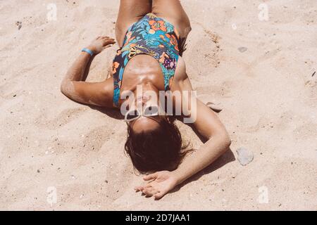 Femme adulte de taille moyenne portant un body couché sur la plage de Valdevaqueros le jour ensoleillé, Tarifa, Espagne Banque D'Images